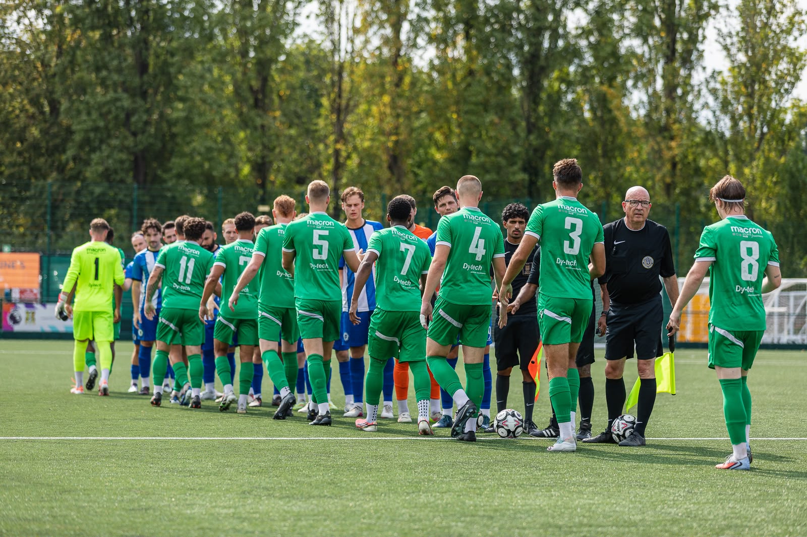 Forest Row players in green kits line up with the opposition and match officials before kick-off